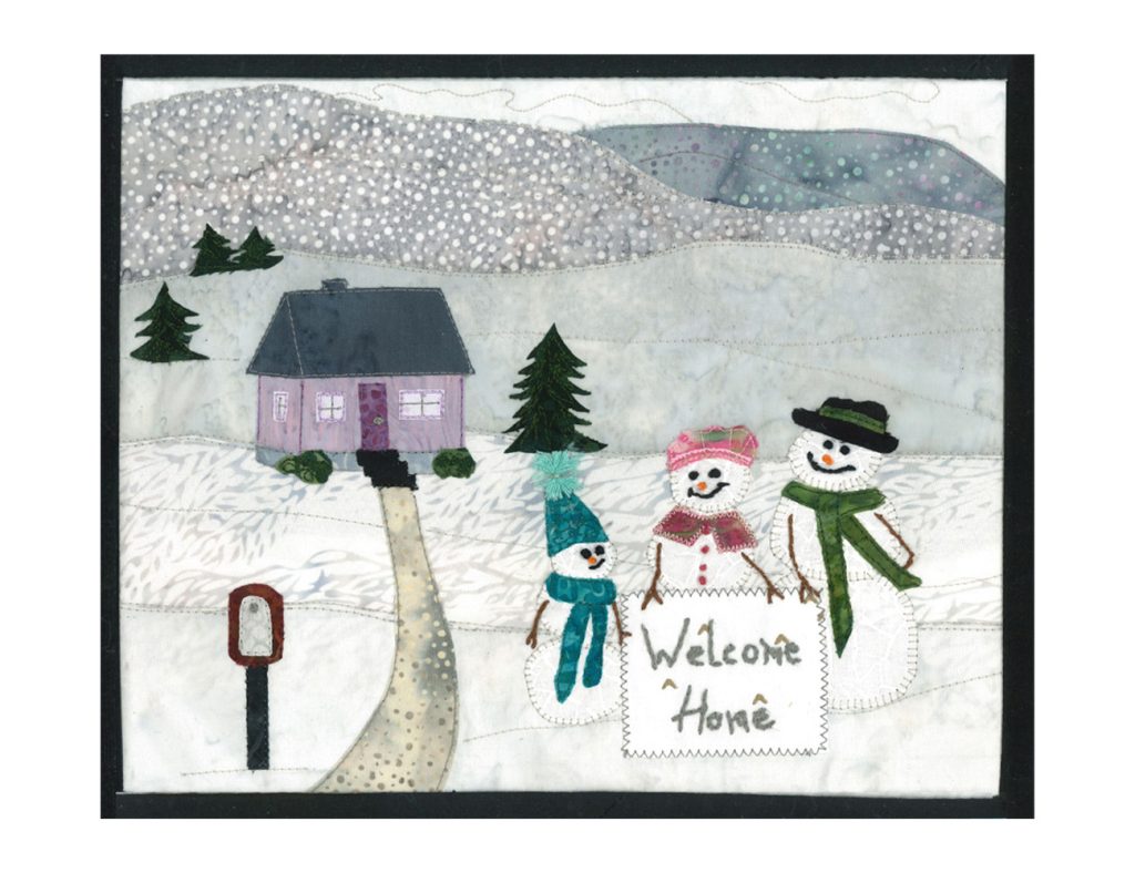 A quilted collage features a snowy scene with a purple house and three snowmen. The snowmen hold a sign that reads "welcome home."