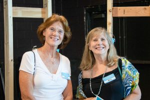 Two women stand shoulder-to-shoulder while smiling for the camera at Habitat Greensboro's Blueprints and Bubbly.