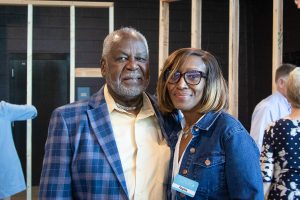 A man and woman stand embracing at the shoulder while wearing blue blazers at Habitat Greensboro's Blueprints and Bubbly event.