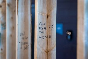 Wooden wall frame with the phrase "God Bless this Home" written in Sharpie next to a heart.