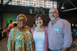 Two women and one man stand shoulder to shoulder at Habitat Greensboro's Blueprints and Bubbly event.