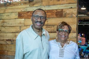 A man and woman stand shoulder-to-shoulder while smiling for the camera at Habitat Greensboro's Blueprints and Bubbly.