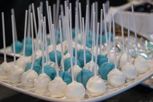 A white plate features an assortment of white and baby blue cake pops