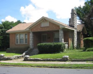 A one story, brick Bungalow with Stone trim sits unoccupied