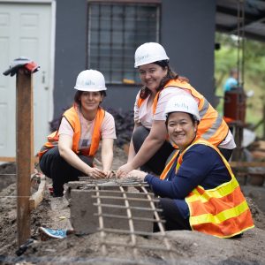 Three volunteers in Honduras working on rebar for a new house foundation